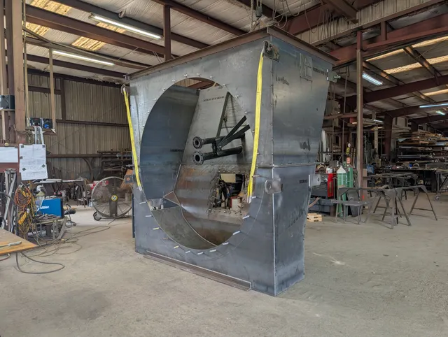 Large rectangular steel fan housing with circular inlet opening under construction in the shop