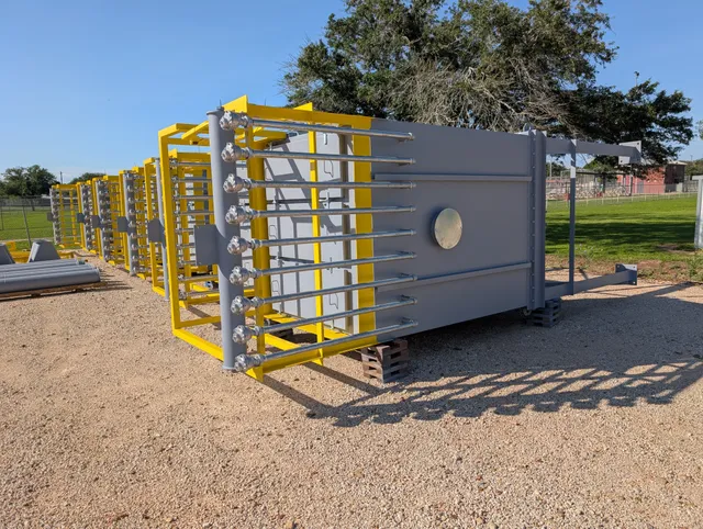 Completed dust collector units with yellow safety-cage access ladders staged in the yard